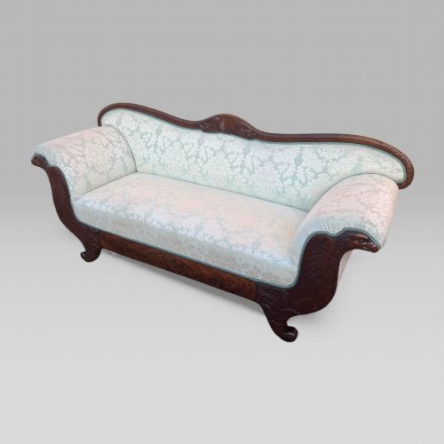 fig 1. A nineteenth-century French Empire flame mahogany sofa featuring carved scroll arms, a serpentine crest, and light blue damask fabric upholstery.