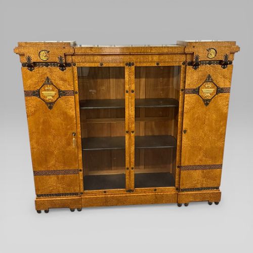 fig 3. A three-piece French Neoclassical office set featuring a satinwood pedestal desk with black trim, a matching glazed cabinet, and an armchair with a green leather seat.