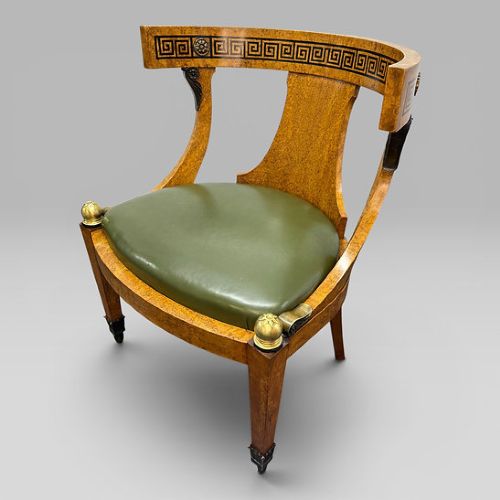 fig 5. A three-piece French Neoclassical office set featuring a satinwood pedestal desk with black trim, a matching glazed cabinet, and an armchair with a green leather seat.