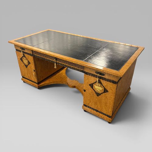 fig 9. A three-piece French Neoclassical office set featuring a satinwood pedestal desk with black trim, a matching glazed cabinet, and an armchair with a green leather seat.