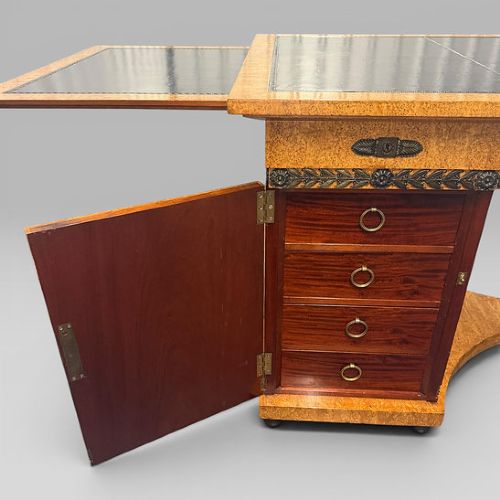 fig 10. A three-piece French Neoclassical office set featuring a satinwood pedestal desk with black trim, a matching glazed cabinet, and an armchair with a green leather seat.