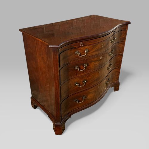fig 1. An 18th-century Georgian mahogany chest of drawers featuring a curved serpentine front, four graduated drawers, brass swan-neck handles, and a pull-out brushing slide.