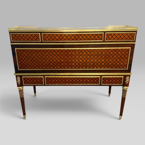 fig 3. A French Louis XVI style cylinder desk featuring detailed geometric diamond parquetry, gilded bronze mounts, a top brass gallery rail, and slender fluted legs.