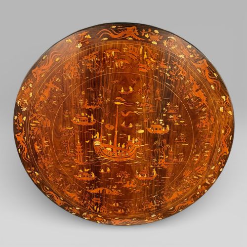 fig 1. A circular dark rosewood centre table featuring detailed marquetry inlays depicting ships, pagodas, and flora.