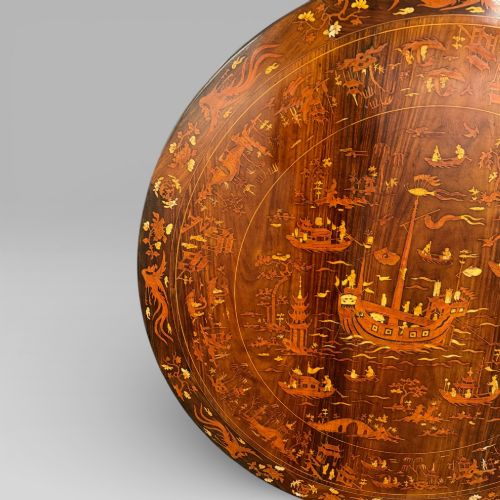 fig 4. A circular dark rosewood centre table featuring detailed marquetry inlays depicting ships, pagodas, and flora.