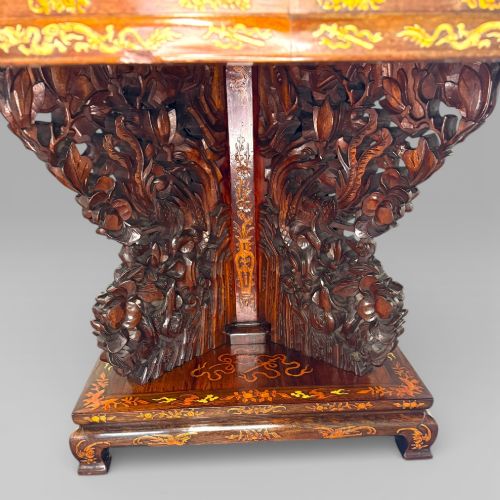 fig 6. A circular dark rosewood centre table featuring detailed marquetry inlays depicting ships, pagodas, and flora.