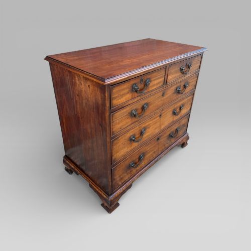 fig 1. An antique George III mahogany chest of drawers featuring a two-over-three drawer layout, brass swan-neck handles, keyhole escutcheons, and bracket feet.