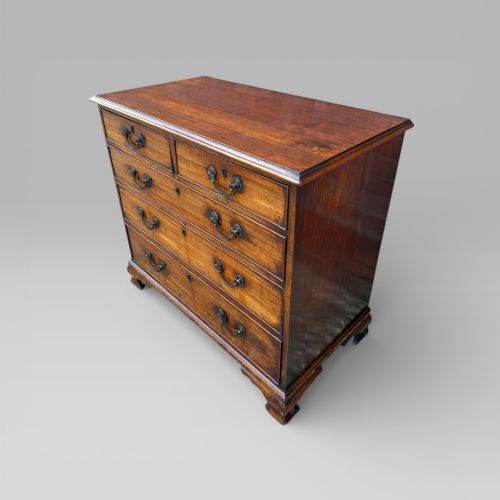 fig 2. An antique George III mahogany chest of drawers featuring a two-over-three drawer layout, brass swan-neck handles, keyhole escutcheons, and bracket feet.
