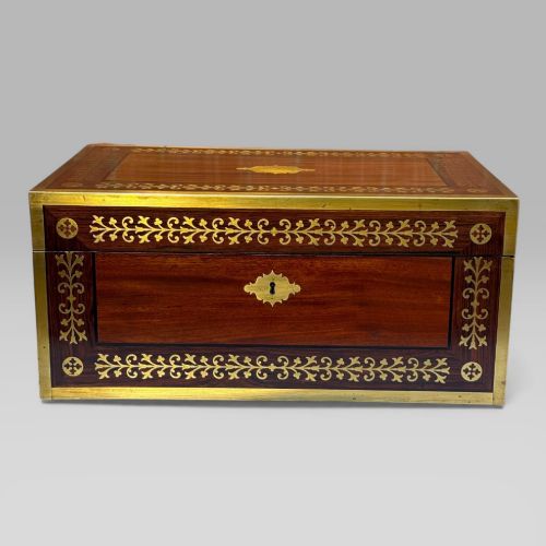 fig 1. A rectangular mahogany and rosewood writing slope featuring brass bound edges, foliate brass inlay borders, a keyhole escutcheon, and an engraved brass cartouche.
