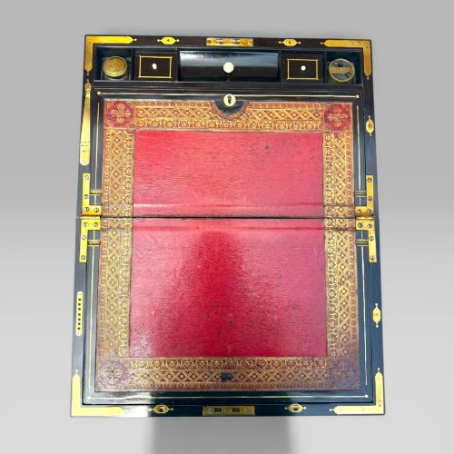 fig 5. A rectangular mahogany and rosewood writing slope featuring brass bound edges, foliate brass inlay borders, a keyhole escutcheon, and an engraved brass cartouche.