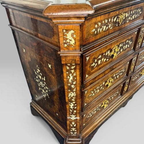 fig 7. An Italian Baroque walnut commode featuring floral bone inlays across six drawer fronts, side panels, and top surface, supported by bracket feet.