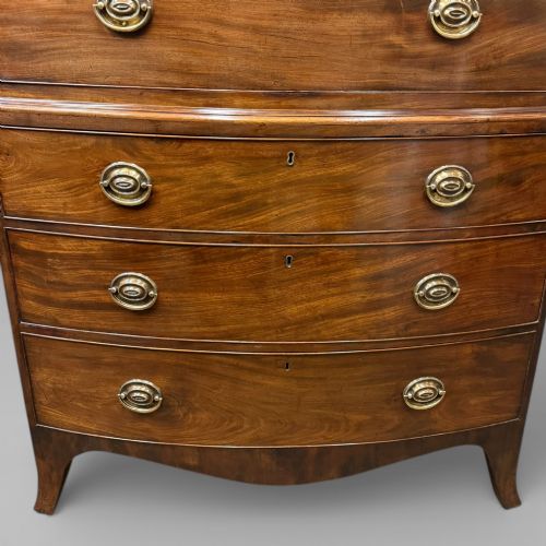 fig 1. An antique Georgian bow-front mahogany chest on chest featuring a carved cornice, two upper short drawers, five long graduating drawers, and brass oval handles.