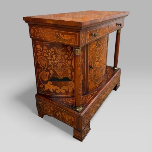 fig 2. An antique Dutch mahogany console cabinet heavily decorated with intricate floral marquetry, featuring a single drawer above a rounded central cupboard door, flanked by turned columns.
