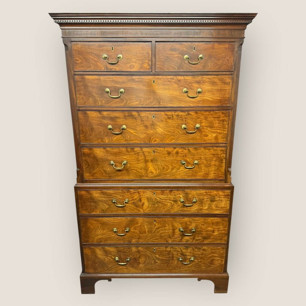 An antique Georgian mahogany eight-drawer chest on chest featuring brass swing handles and a dental cornice.