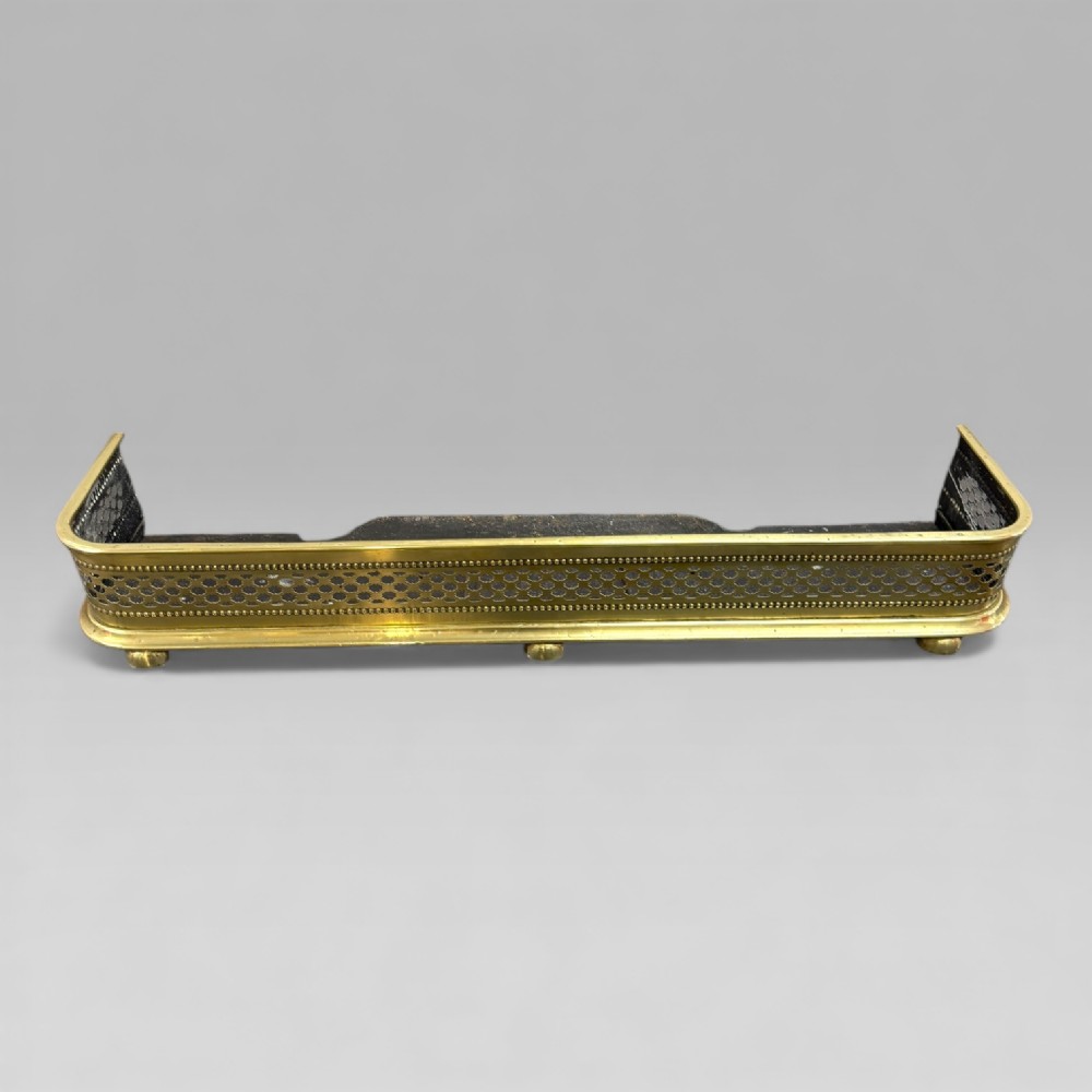 A Victorian rectangular brass fire fender featuring a pierced geometric band, beaded moulding, and low raised feet.