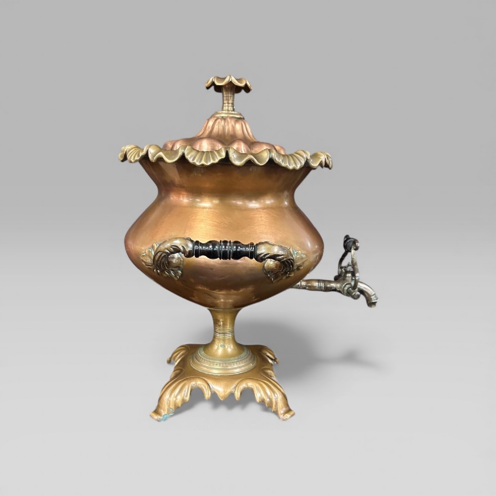 An antique Victorian copper samovar featuring a fluted lid, scalloped brass rim, cast brass side handles, a brass spigot, and a four-footed scroll base. View II