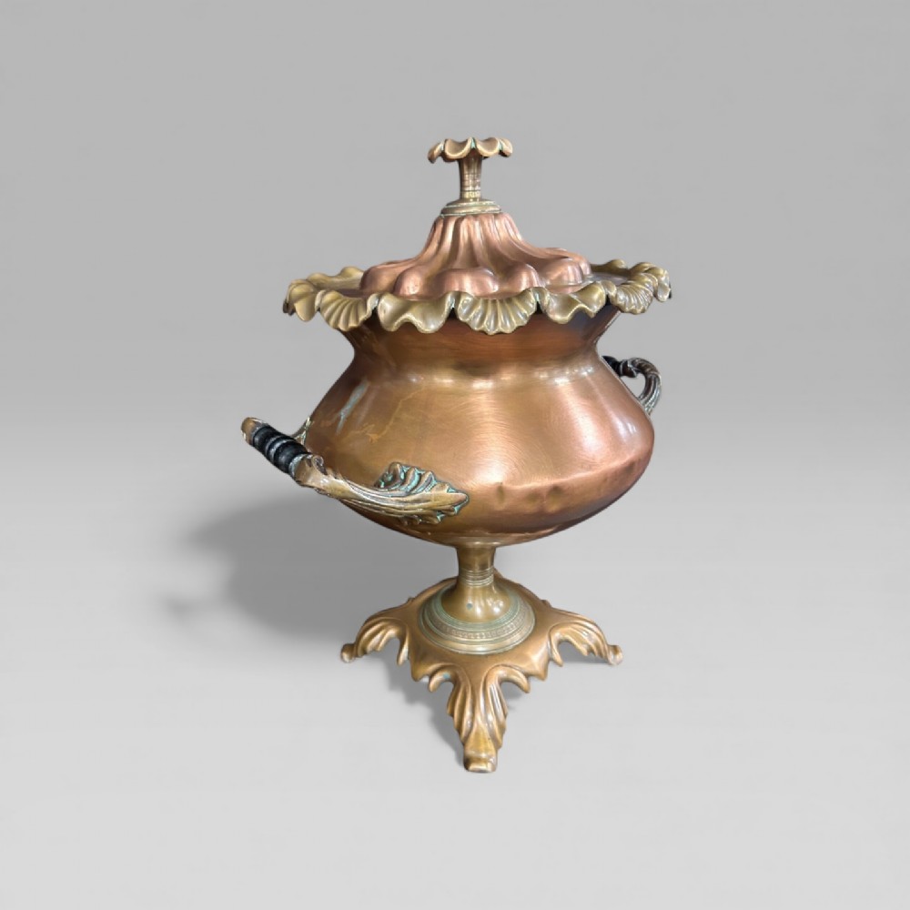 An antique Victorian copper samovar featuring a fluted lid, scalloped brass rim, cast brass side handles, a brass spigot, and a four-footed scroll base. View VI