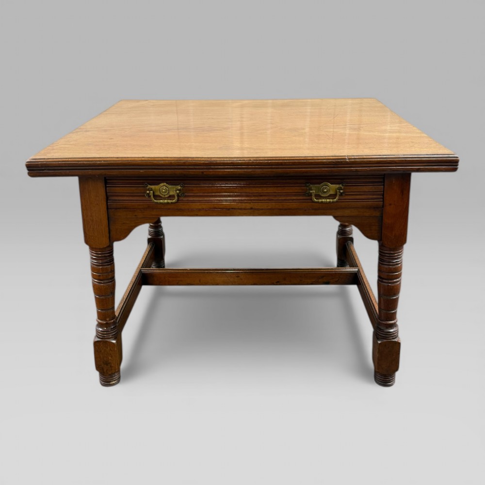 An antique walnut coffee table featuring turned legs, a rectangular top, brass drop handles, and an H-stretcher base.