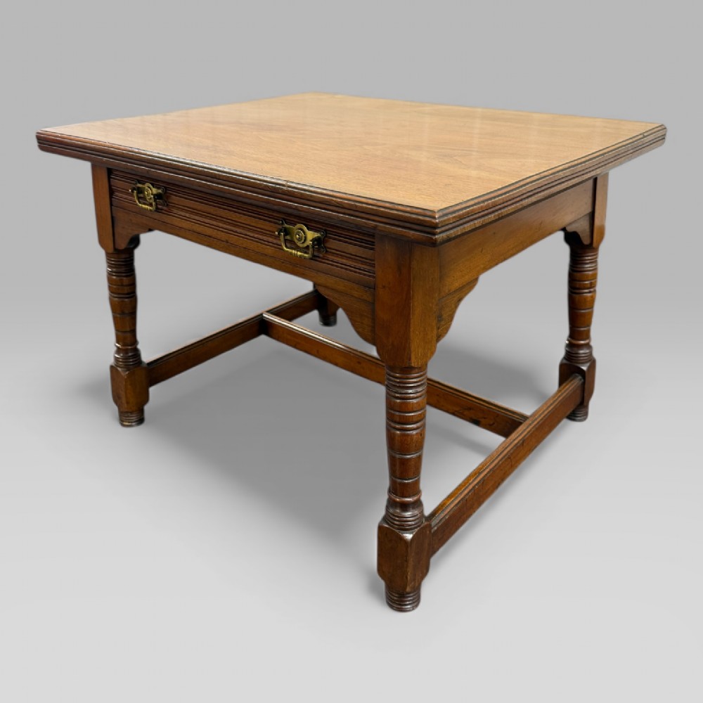 An antique walnut coffee table featuring turned legs, a rectangular top, brass drop handles, and an H-stretcher base. View III