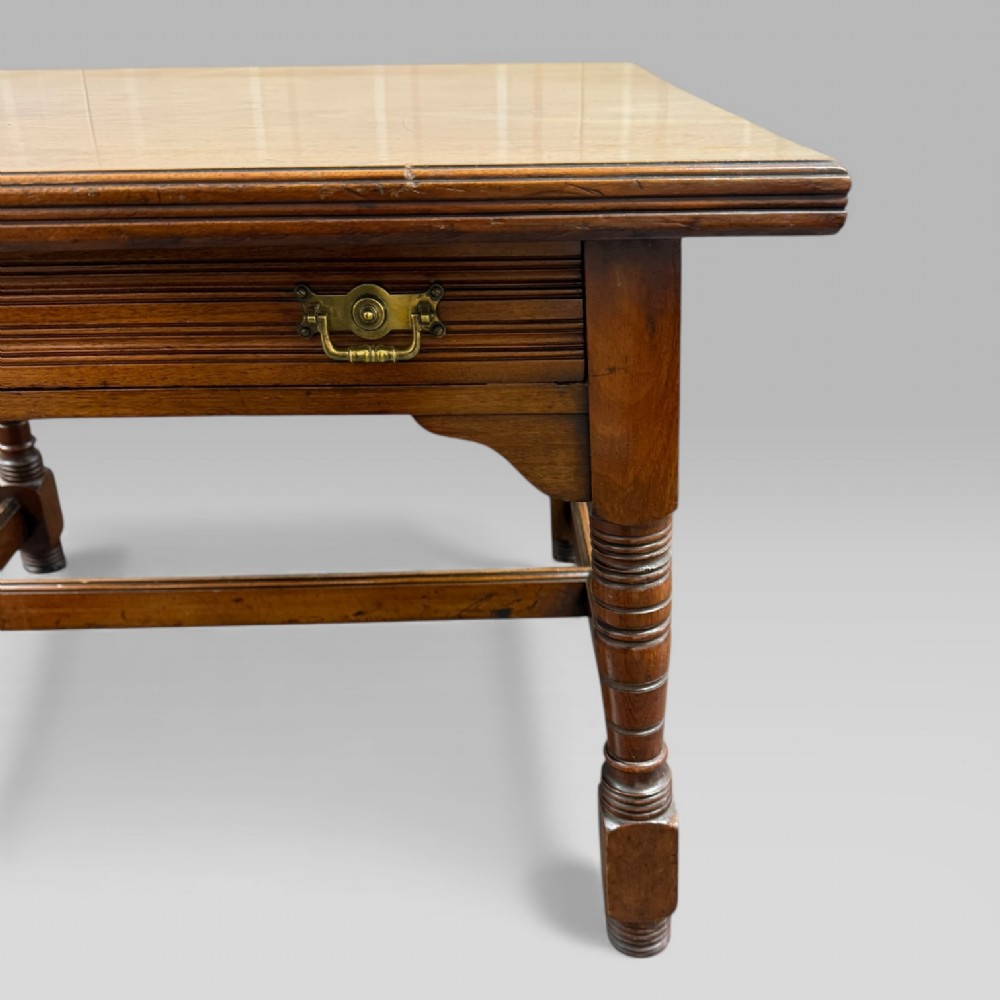 An antique walnut coffee table featuring turned legs, a rectangular top, brass drop handles, and an H-stretcher base. View V