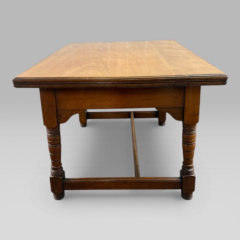 An antique walnut coffee table featuring turned legs, a rectangular top, brass drop handles, and an H-stretcher base. View VII