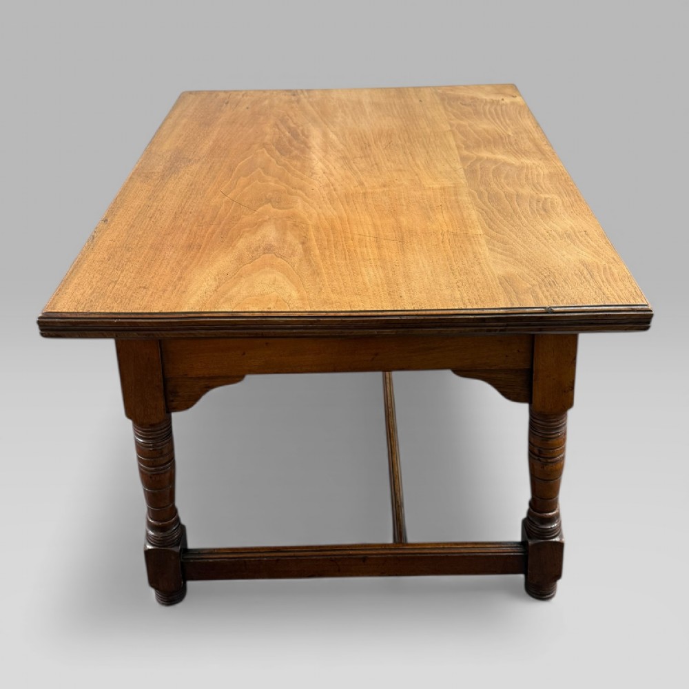 An antique walnut coffee table featuring turned legs, a rectangular top, brass drop handles, and an H-stretcher base. View X