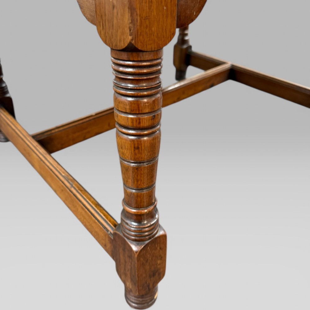 An antique walnut coffee table featuring turned legs, a rectangular top, brass drop handles, and an H-stretcher base. View XI