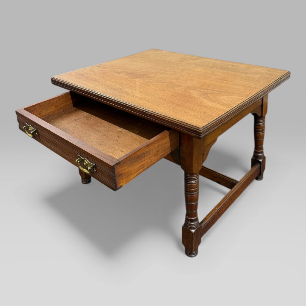 An antique walnut coffee table featuring turned legs, a rectangular top, brass drop handles, and an H-stretcher base. View XII