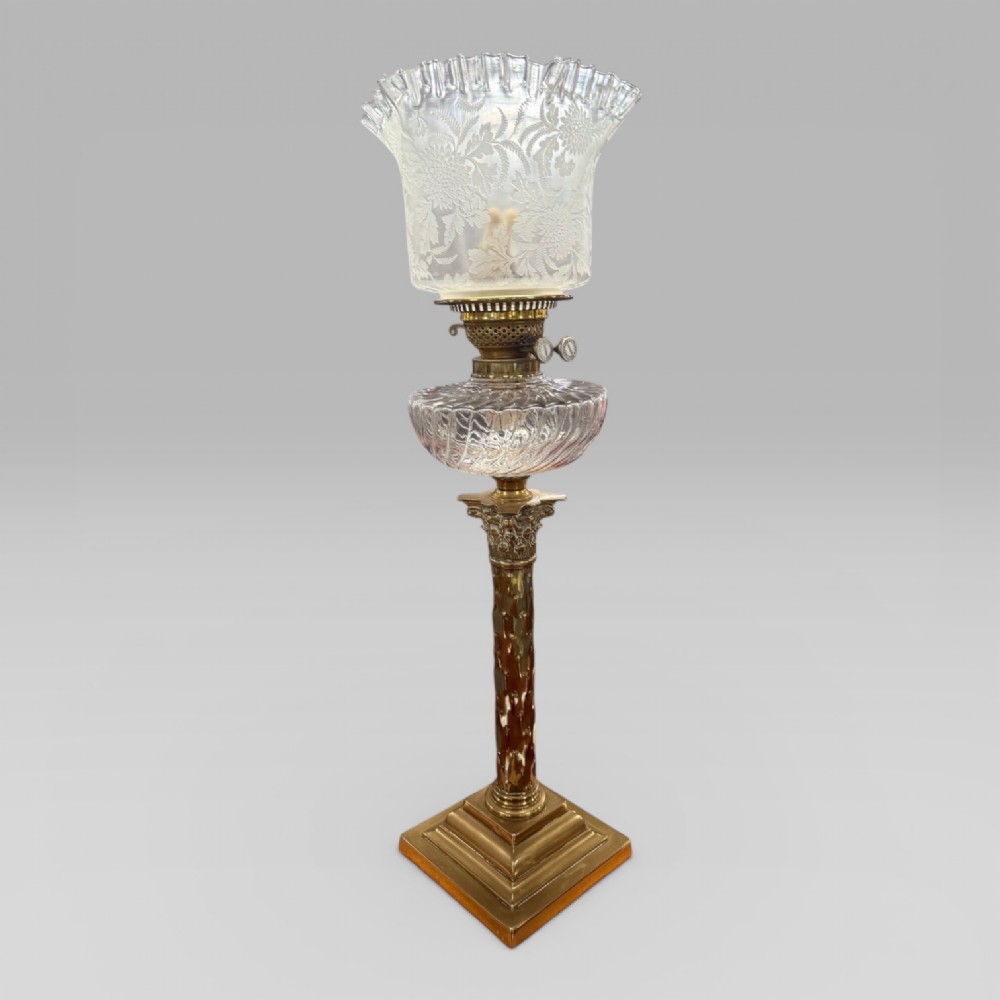 An antique Victorian oil lamp featuring a Corinthian style brass column base, clear glass reservoir, and an etched glass tulip shade with a frilled top rim. View II
