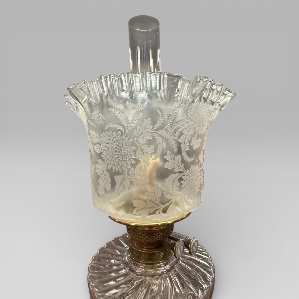 An antique Victorian oil lamp featuring a Corinthian style brass column base, clear glass reservoir, and an etched glass tulip shade with a frilled top rim. View VI