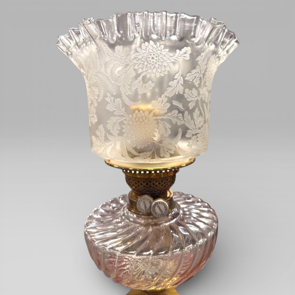 An antique Victorian oil lamp featuring a Corinthian style brass column base, clear glass reservoir, and an etched glass tulip shade with a frilled top rim. View VIII