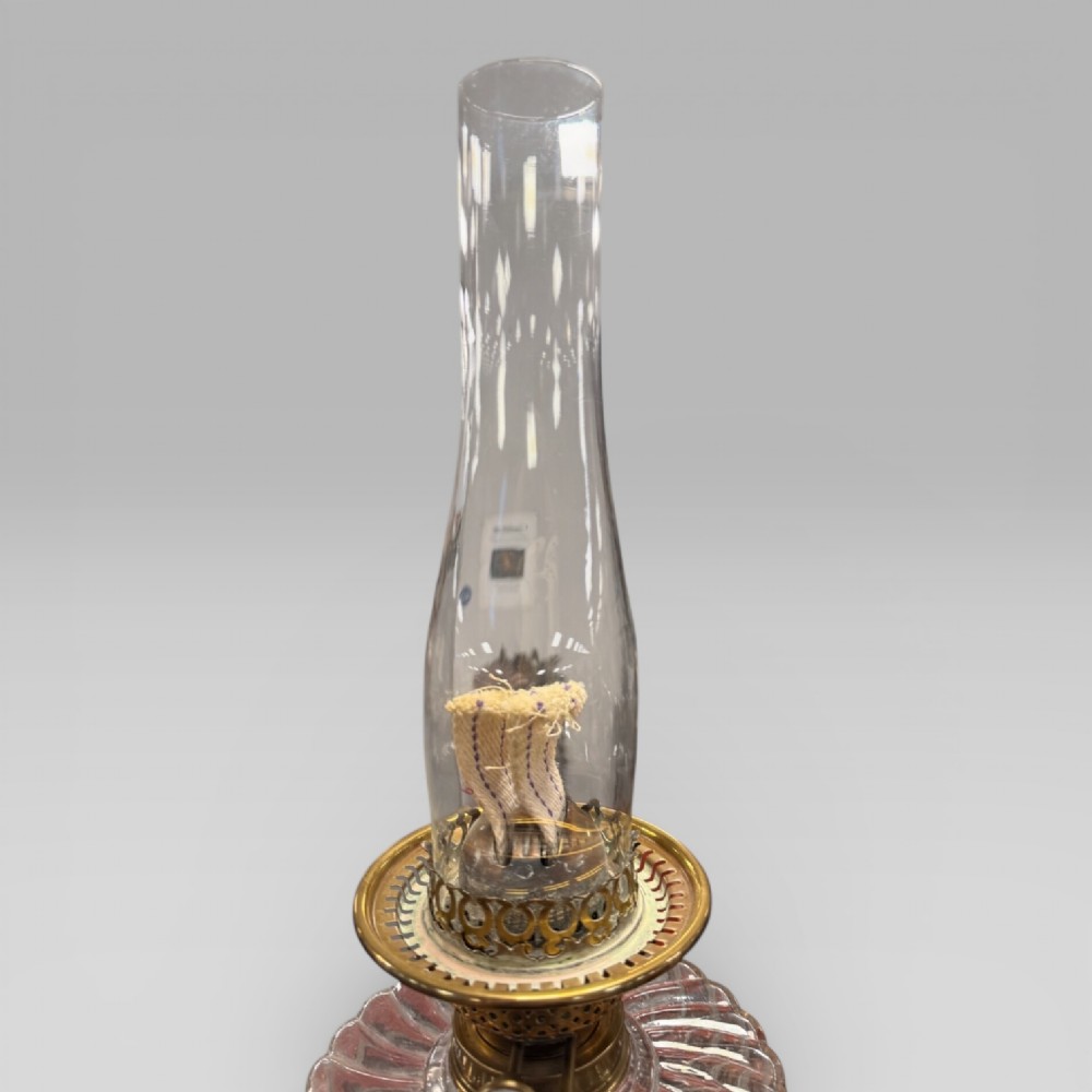 An antique Victorian oil lamp featuring a Corinthian style brass column base, clear glass reservoir, and an etched glass tulip shade with a frilled top rim. View XII