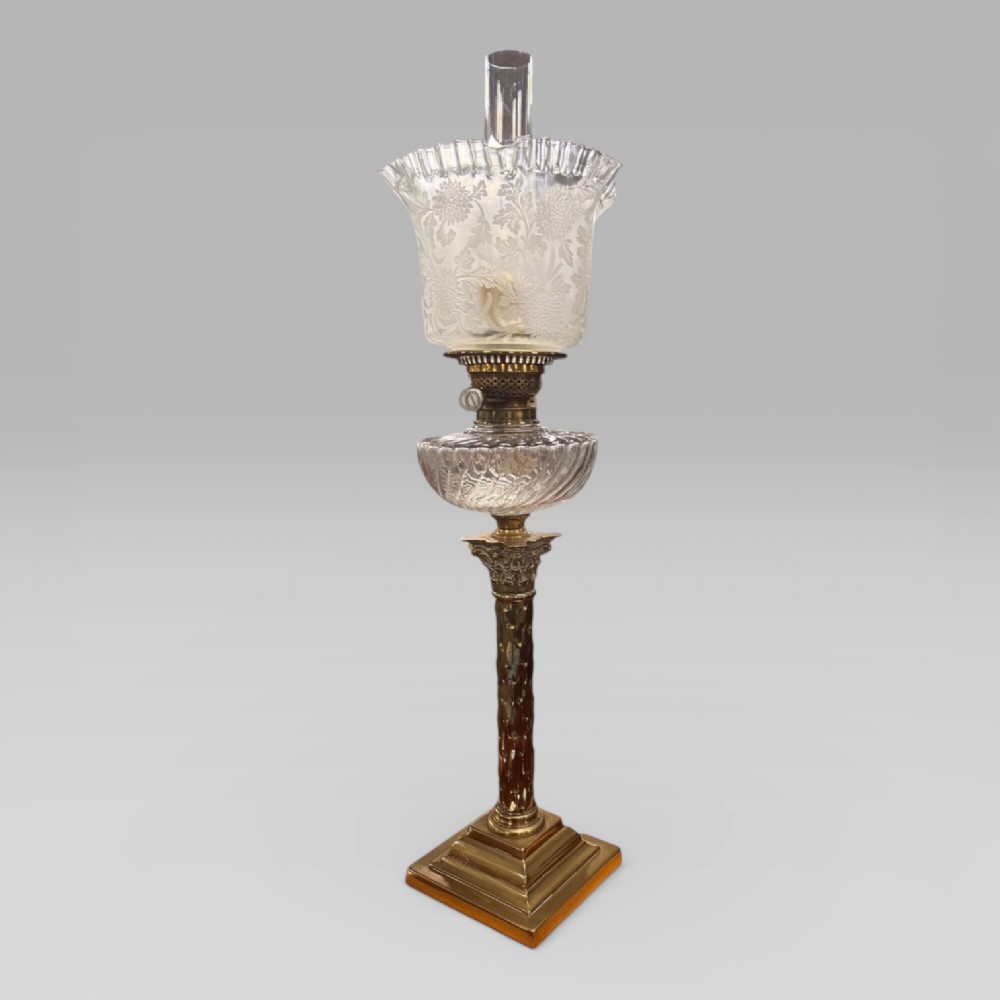 An antique Victorian oil lamp featuring a Corinthian style brass column base, clear glass reservoir, and an etched glass tulip shade with a frilled top rim. View XV