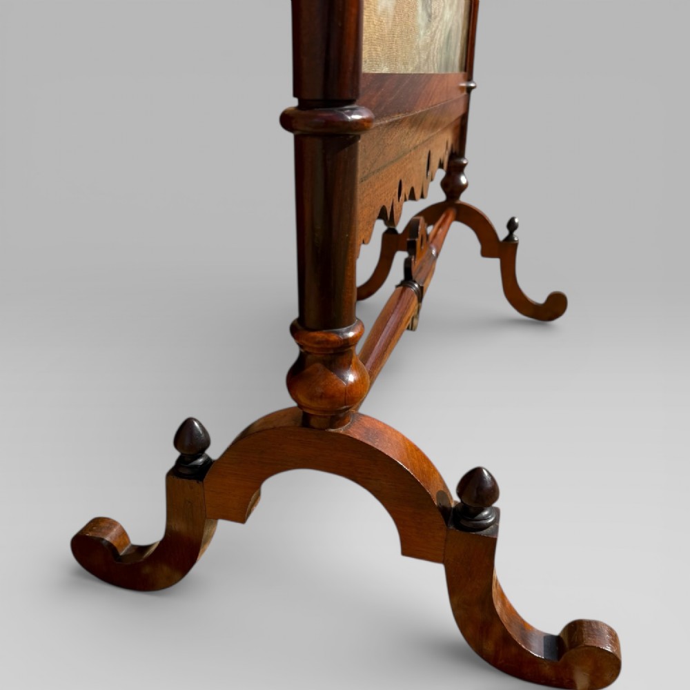 A Victorian rosewood cheval fire screen featuring a carved wooden frame with finials and an embroidered textile panel depicting figures near a coastal cottage. View IX