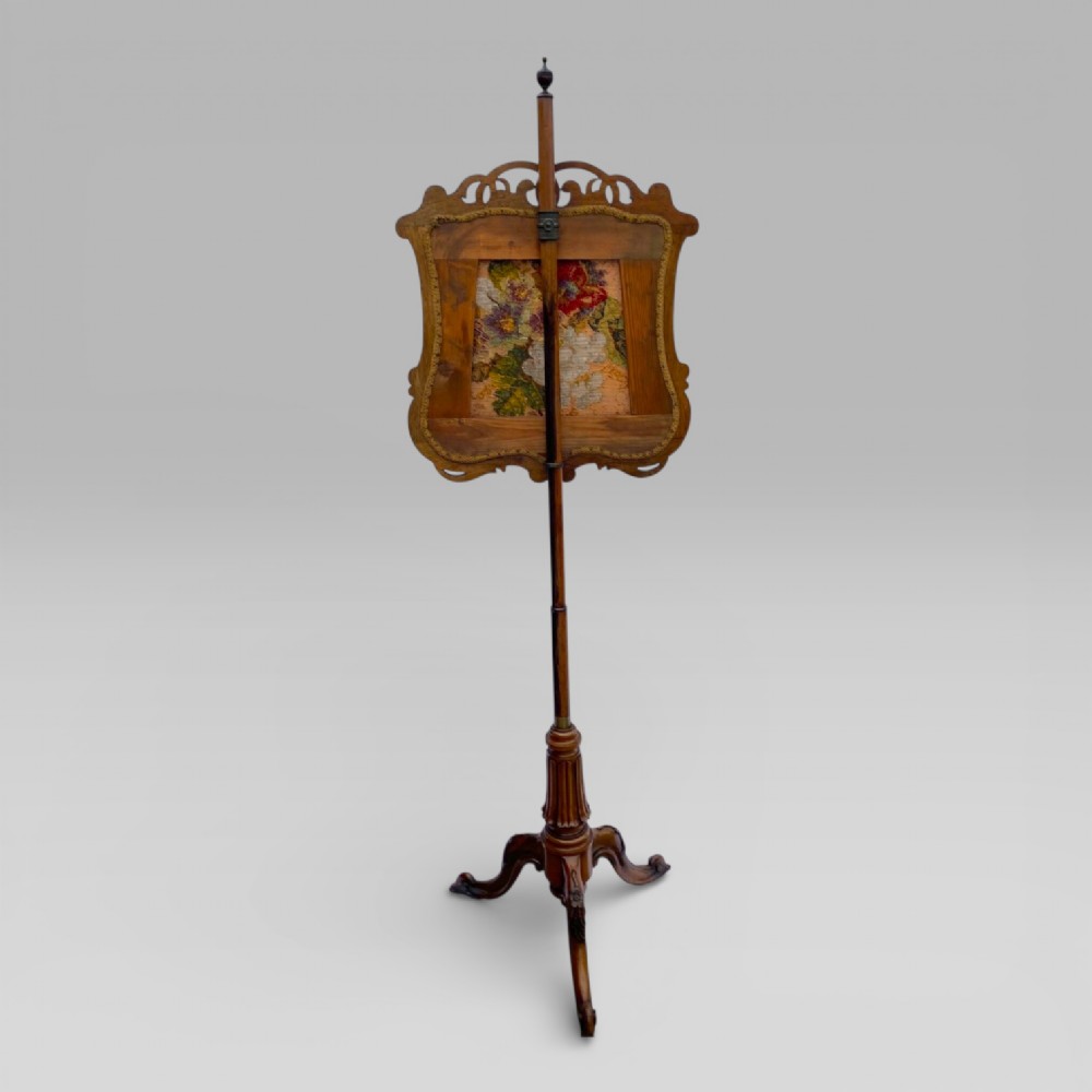 An antique Victorian rosewood pole screen featuring a carved floral tapestry panel mounted on an adjustable central column with a carved tripod base. View II