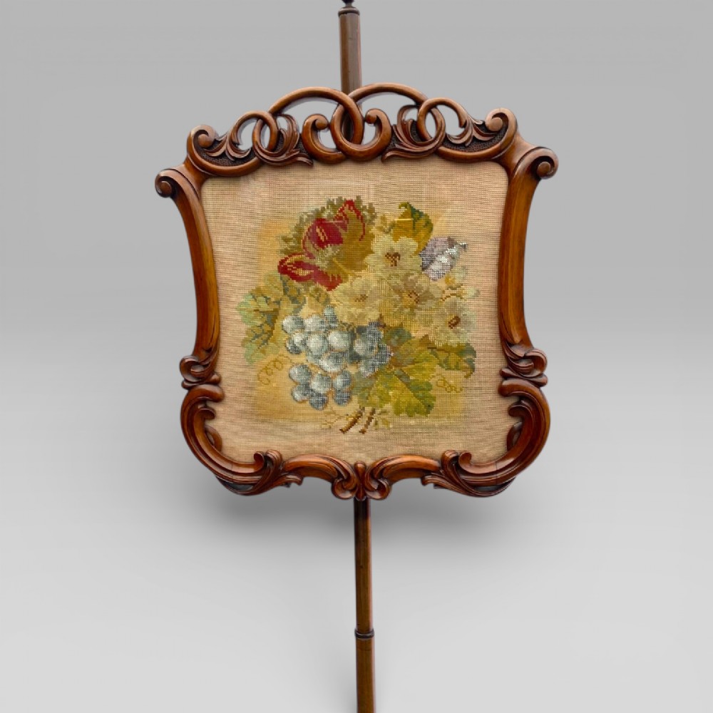An antique Victorian rosewood pole screen featuring a carved floral tapestry panel mounted on an adjustable central column with a carved tripod base. View III