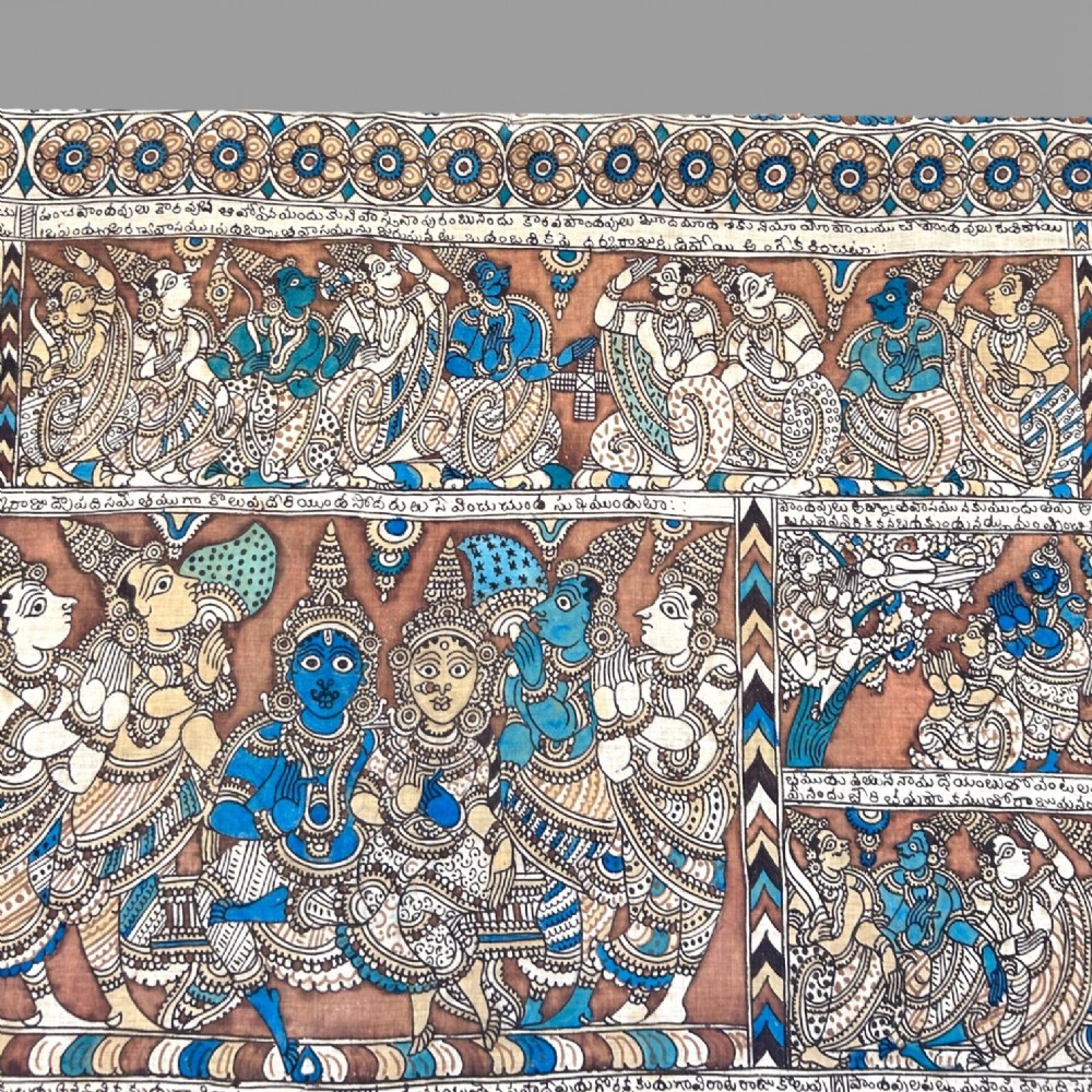 A rectangular Indian Kalamkari cotton textile displaying narrative panels filled with hand-drawn Hindu deities framed by a decorative floral border in blue, beige, and terracotta tones. View V