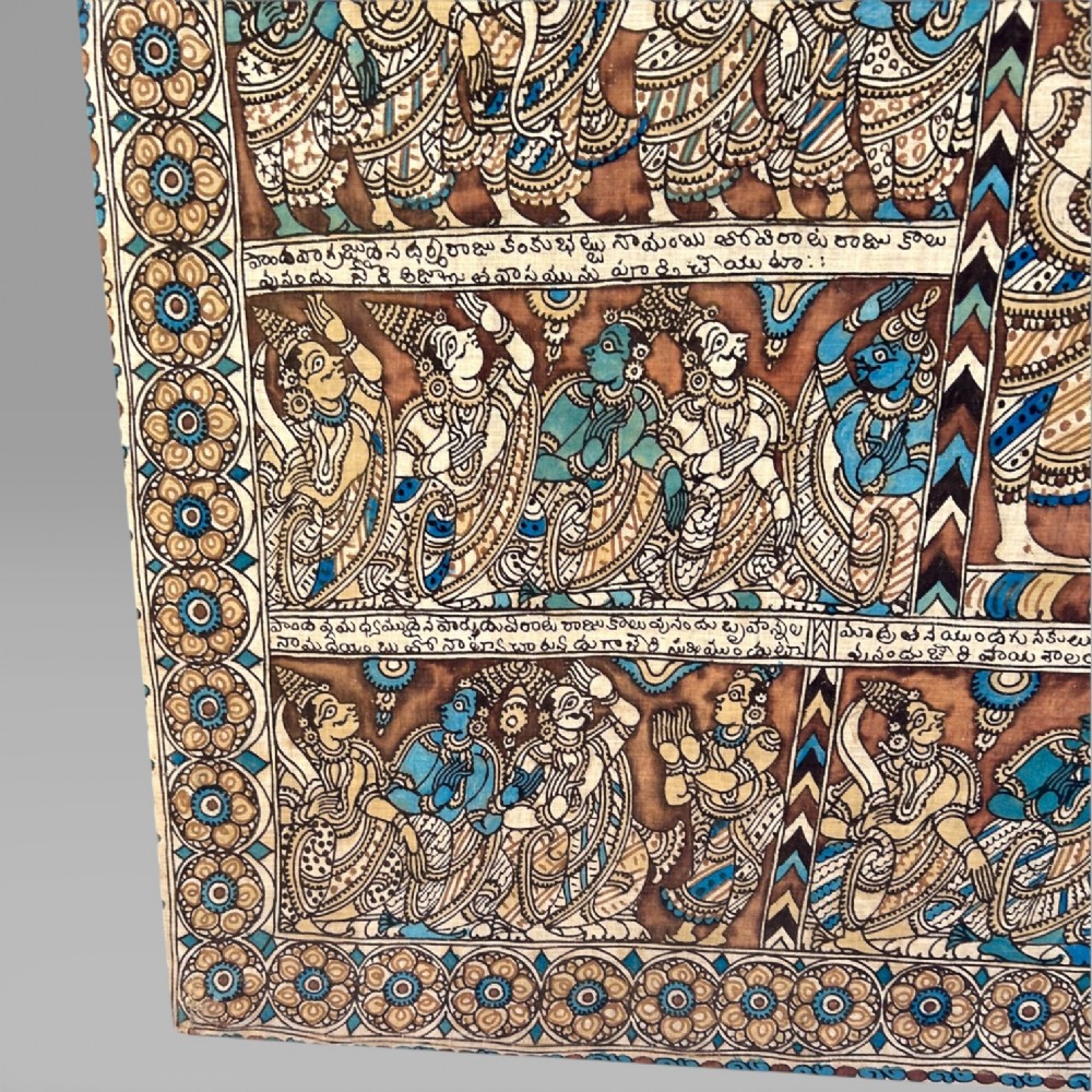 A rectangular Indian Kalamkari cotton textile displaying narrative panels filled with hand-drawn Hindu deities framed by a decorative floral border in blue, beige, and terracotta tones. View IX