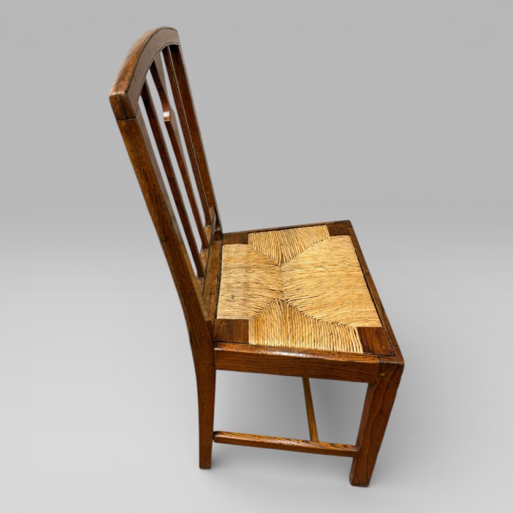A 19th-century elm side chair featuring a woven rush seat, vertical back slats, and straight legs connected by stretchers. View V