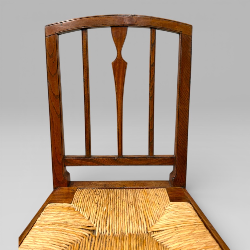 A 19th-century elm side chair featuring a woven rush seat, vertical back slats, and straight legs connected by stretchers. View VI