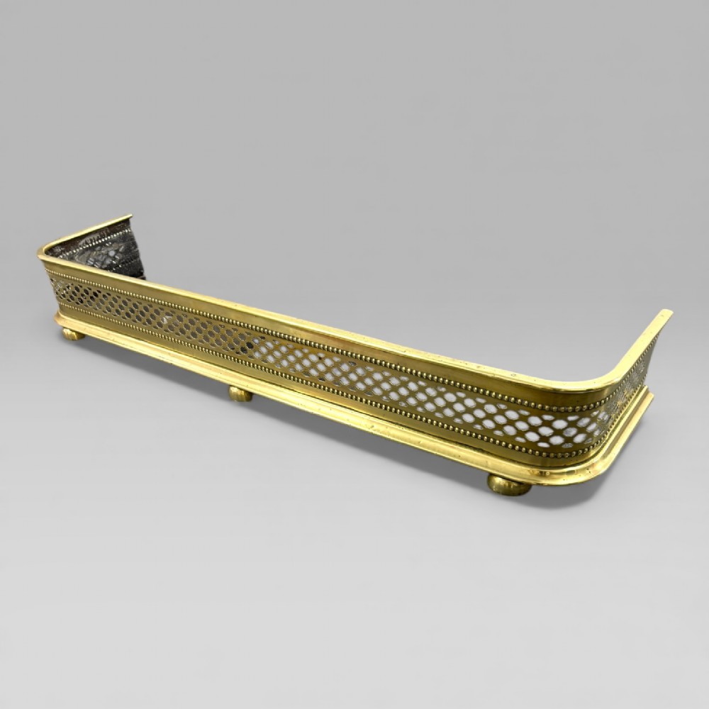 A long Victorian brass fire fender featuring a pierced lattice pattern, beaded edge trim, and low support feet. View II