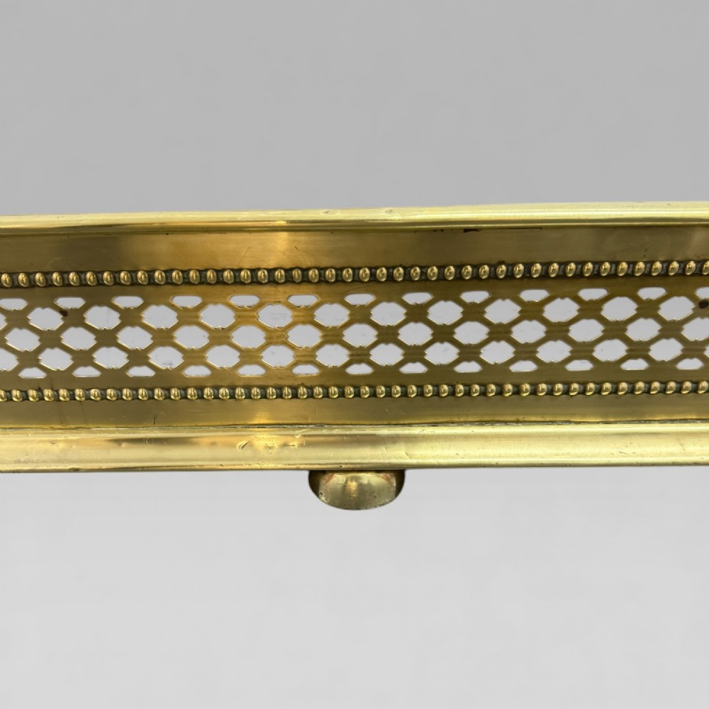 A long Victorian brass fire fender featuring a pierced lattice pattern, beaded edge trim, and low support feet. View IV