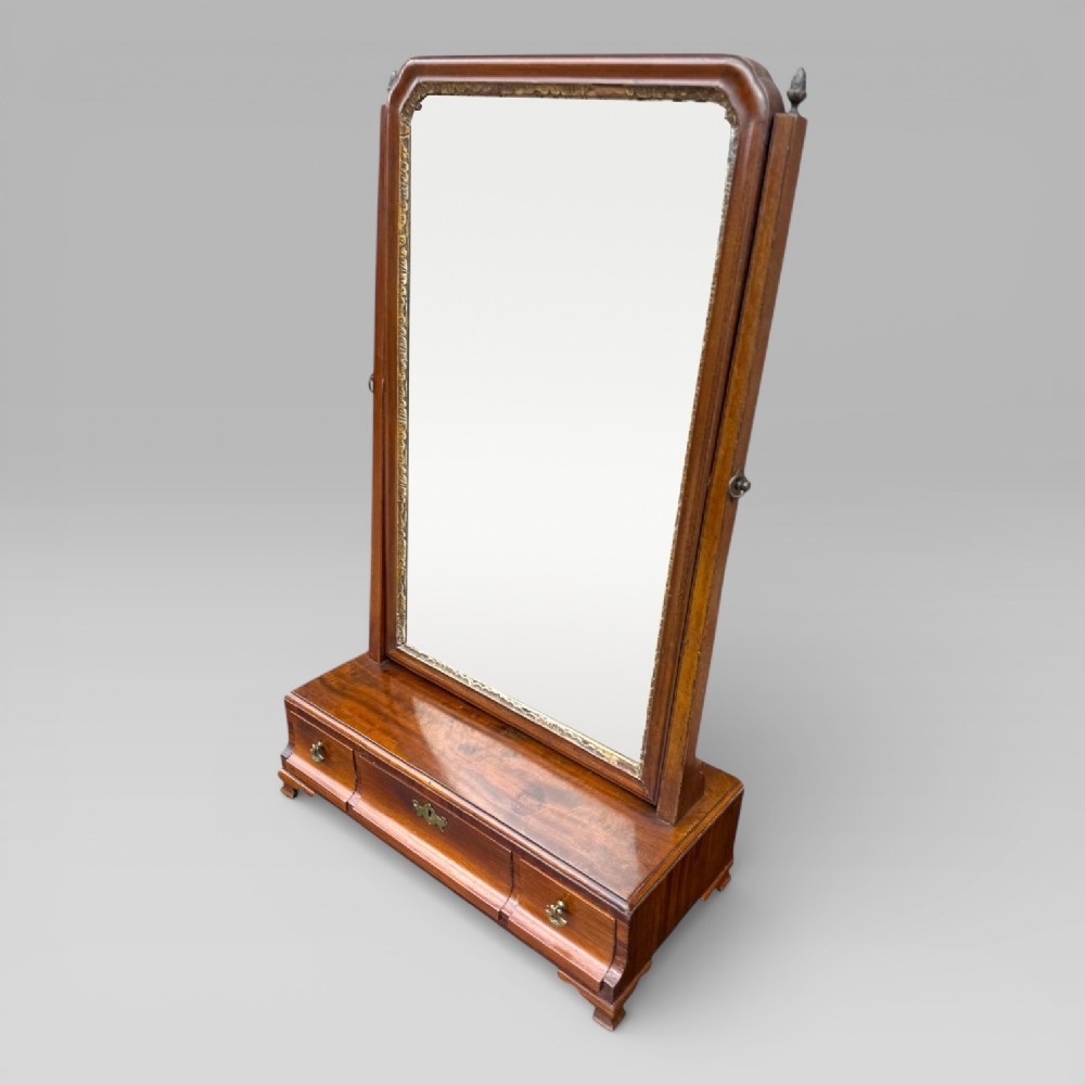 An 18th-century Georgian mahogany dressing table mirror featuring an arched glass frame with a gilt inner slip, brass finials, and a plinth base fitted with drawers. View II