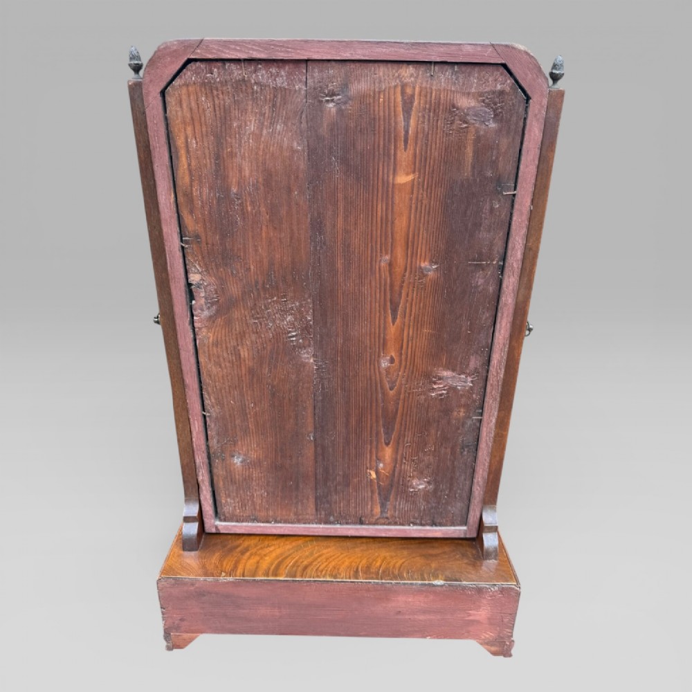 An 18th-century Georgian mahogany dressing table mirror featuring an arched glass frame with a gilt inner slip, brass finials, and a plinth base fitted with drawers. View V