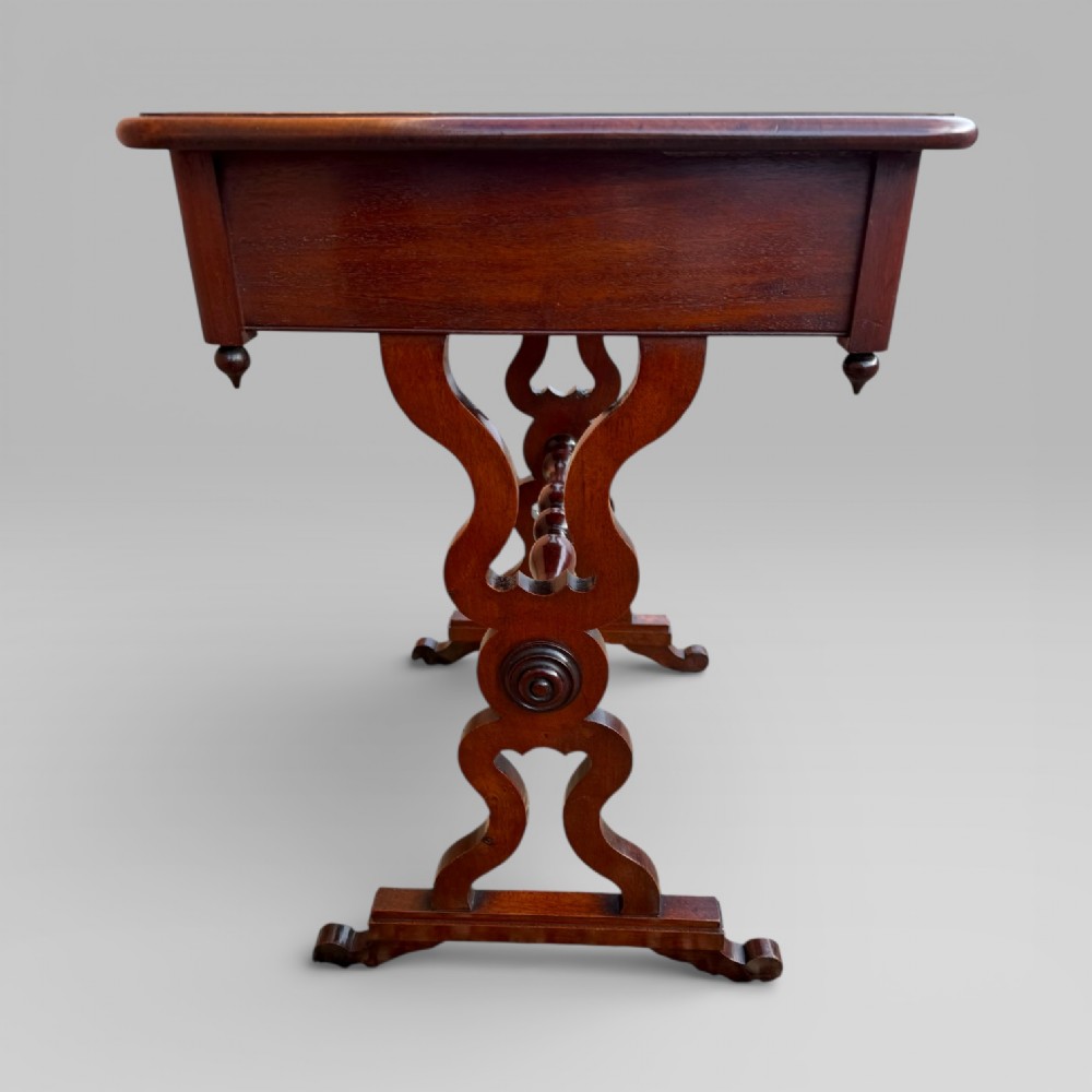 A Victorian mahogany centre table featuring a rectangular top with moulded edge, two frieze drawers with brass drop handles, carved shaped end supports, and a turned stretcher. View V