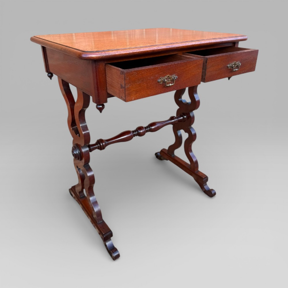 A Victorian mahogany centre table featuring a rectangular top with moulded edge, two frieze drawers with brass drop handles, carved shaped end supports, and a turned stretcher. View VI
