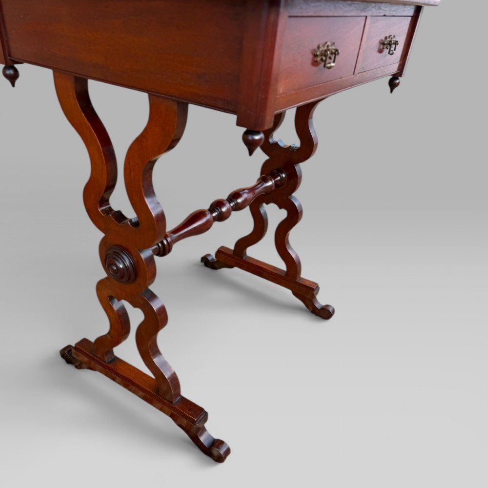A Victorian mahogany centre table featuring a rectangular top with moulded edge, two frieze drawers with brass drop handles, carved shaped end supports, and a turned stretcher. View IX