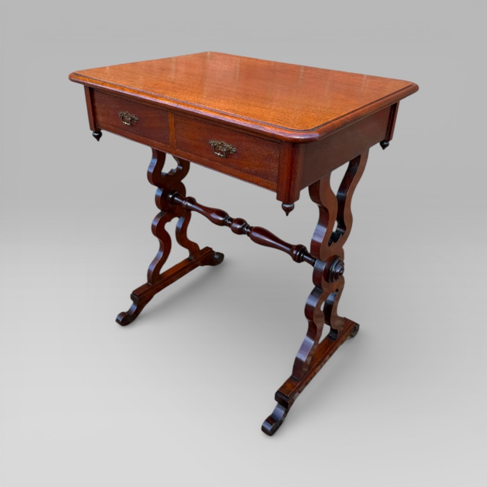 A Victorian mahogany centre table featuring a rectangular top with moulded edge, two frieze drawers with brass drop handles, carved shaped end supports, and a turned stretcher. View XI
