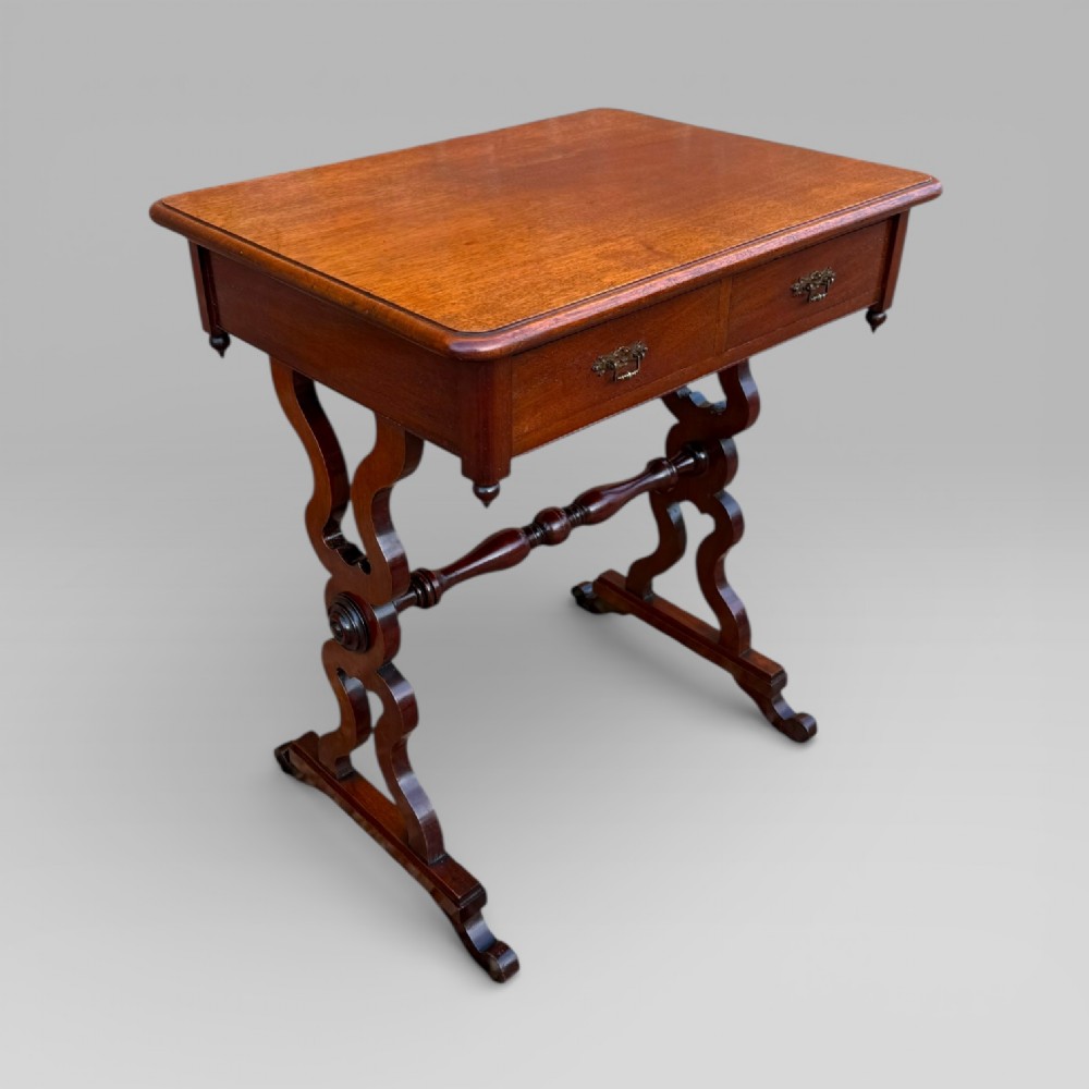A Victorian mahogany centre table featuring a rectangular top with moulded edge, two frieze drawers with brass drop handles, carved shaped end supports, and a turned stretcher. View XII