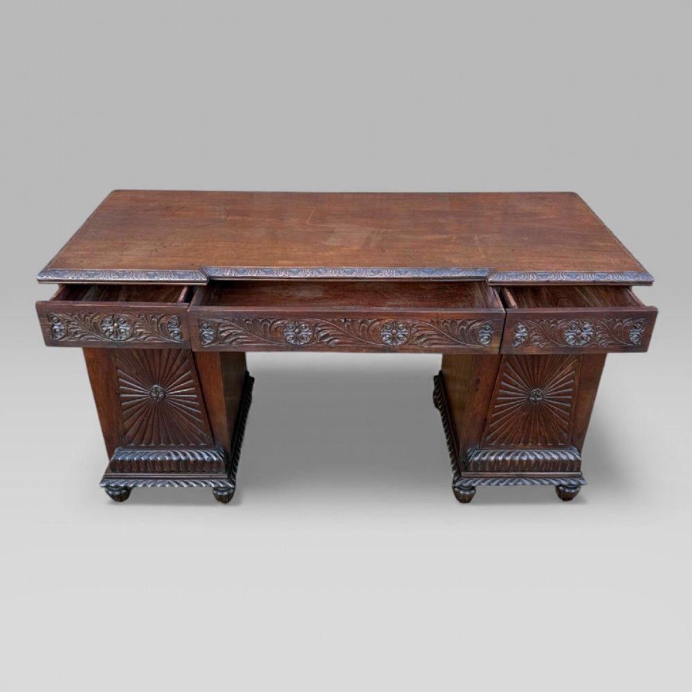 A dark carved padouk wood sideboard featuring intricate floral frieze carvings, sunburst panel pedestals, and a central kneehole design. View III